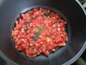锅里倒入三四十毫升左右的油，倒入番茄丁煸炒，一边炒一边用锅铲压一压，让番茄煮得熟烂。