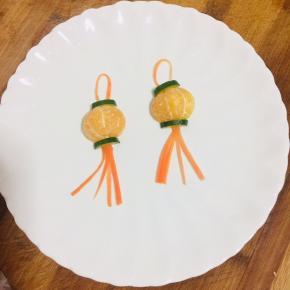 把胡萝卜须摆在桔子下端，再取一根胡萝卜丝弯曲成半圆形，摆在桔子上端！