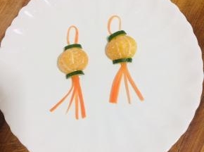 把胡萝卜须摆在桔子下端，再取一根胡萝卜丝弯曲成半圆形，摆在桔子上端！