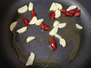 炒锅内倒适量的食用油烧热，下入蒜片和干红辣椒炒香。