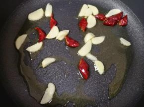炒锅内倒适量的食用油烧热，下入蒜片和干红辣椒炒香。