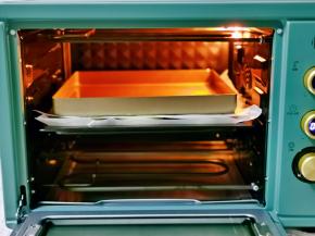 二发好后，先盖上一张油纸，再放上一个烤盘压住油纸，如图所示。