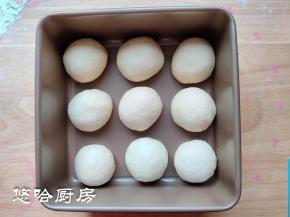 松弛后的面团拍打排气，翻面后向里折起，再次滚圆，摆放在模具中，进行二次发酵。