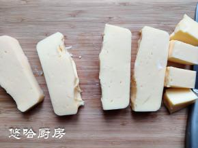 冷藏的奶酪糊倒扣在案板上，用刀切成小块。