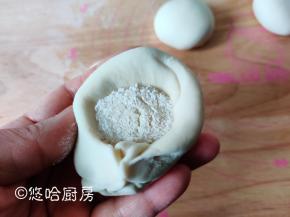 分割后的面团大致揉匀、擀开，包入适量的白糖馅，捏成小包子的形状。