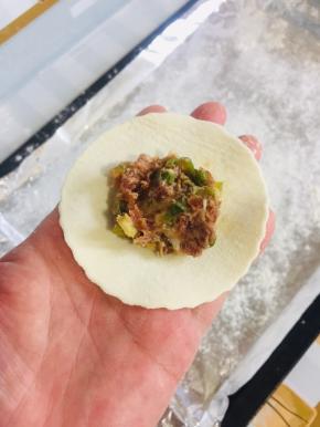 取一块饺子皮，放入一勺茄子猪肉馅儿！