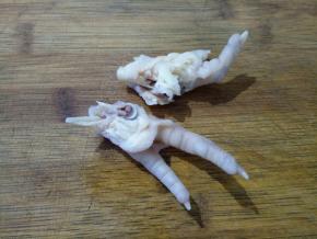 鸡爪洗干净，我偷懒没有剪趾甲，刮去表面残余的黄皮，切成两半，这样入味一点。