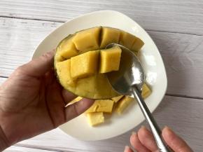 把芒果对半切下，划出格子，翻出果肉，把芒果丁用铁勺挖下来；