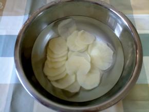 土豆削皮，然后用擦丝器擦片的刀口擦出薄片来。然后在水里泡几分钟，泡去一些淀粉