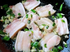 锅中倒入底油加热放入葱姜蒜爆香再放入五花肉炒至变色