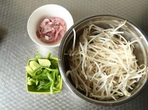 准备材料，豆芽挑干净，将头尾摘掉一些，清洗干净备用。肉切成肉丝。青椒去柄洗净切丝。