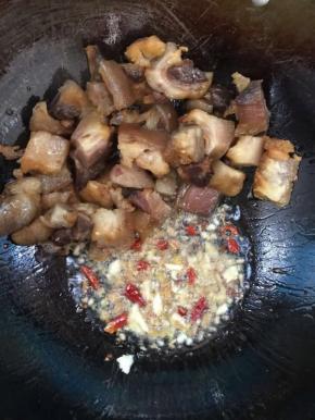 把煸炒好的腊猪蹄拨到一边，放入生姜，蒜瓣，花椒，干辣椒炒出香味儿后，再和腊猪蹄混合一起翻炒均匀！

