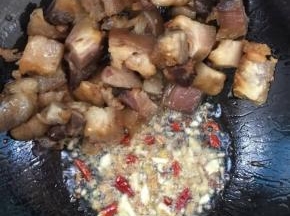 把煸炒好的腊猪蹄拨到一边，放入生姜，蒜瓣，花椒，干辣椒炒出香味儿后，再和腊猪蹄混合一起翻炒均匀！

