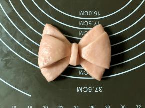 然后把最上面的那根折叠向下，多余的部分折叠到后面，相当于绕一圈，接头藏在后边，蝴蝶结造型就做好了。