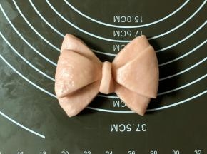 然后把最上面的那根折叠向下，多余的部分折叠到后面，相当于绕一圈，接头藏在后边，蝴蝶结造型就做好了。