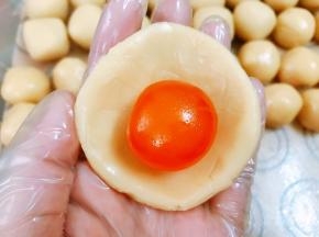 纯白莲蓉馅分为20份，取一份压扁包入一个咸蛋黄包紧收口滚圆