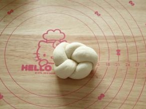 然后将右边的长条尾部往面团底下压，左边的长条尾部从上方塞入之前的圆孔中，将左右两头的尾部捏紧即可。略微整理，就是5瓣花型，如果搓的长条够长，可以制作成6瓣花型。