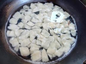 水烧开后，先倒1汤匙的玉米油，然后再倒入面片煮，这样面片不容易粘连。用锅铲扒拉几下，让面片散开，然后盖上锅盖煮到沸腾后再煮2分钟，然后加一碗凉水，再锅铲扒拉几下，盖上煮到沸腾，最后开盖再煮两三分钟，煮到面片全浮起来，半透明状，跟煮饺子差不多。