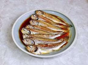 取出蒸好的鱼，把姜丝葱段夹掉，盘子里的汤汁倒掉，淋上一勺生抽，再浇上一勺热油。