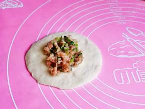 取一块面团，擀成面饼，加入适当的肉馅。