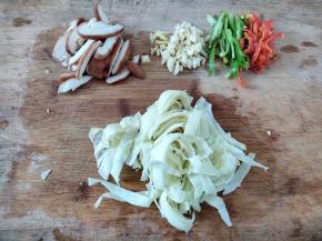 配菜都洗干净，新鲜香菇切片，包菜切丝，青红辣椒切丝，姜和蒜切碎。