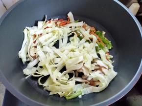 接着下辣椒、香菇和包菜，翻炒至断生。