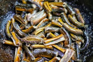 锅中热油，放入鳝鱼煎至变硬，