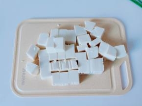 豆腐对半切开再切小块。【用刀在豆腐盒的两边各划一下，豆腐从盒子里轻轻松松就拿出来】