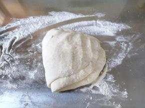 案板上撒一些干粉，将面团移到案板上，先轻轻拍平排气，然后上下左右折叠重复两三次。