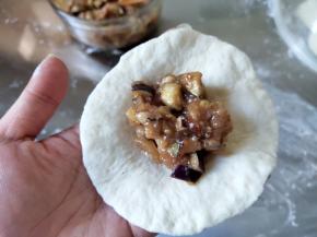 取一个小面团，擀成10-12cm直径的圆片，边缘要捏薄，加入适量馅。