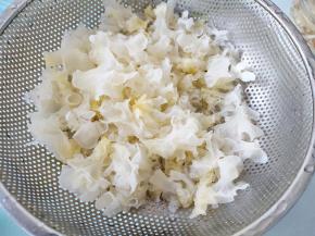 新鲜银耳剪去菌脚，撕成小片，洗干净晾下水。