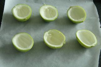 将柠檬用盐搓洗干净外壳，然后对半切开。戴着PVC手套用小勺子沿着柠檬皮和果肉的间隙将内部的柠檬果肉全部取出！掏出的果肉可以泡茶喝！将柠檬壳排入垫了油纸的烤盘中。