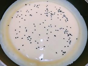 油热后倒入面糊晃平，撒上熟黑芝麻