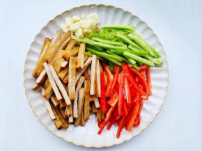 香干、辣椒洗净切条，蒜切片。