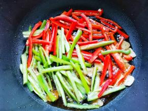 锅内热油下蒜片爆香，加辣椒丝炒至7分熟，