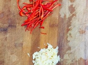 红辣椒去蒂去籽切成丝，蒜瓣拍碎剁成碎末备用！