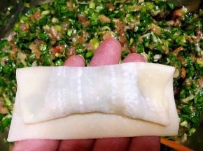 馄饨皮包好馅料从一个方向卷至另一端