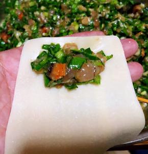 取适量的馅料放入馄饨皮一端的中间