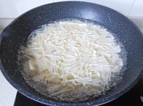 豆腐炖煮一会儿后加入金针菇。