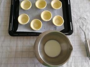 7个挞皮取出，放在垫了油纸的烤盘上！开工前先预热烤箱，上下200度。然后将牛奶50克倒入干净无水盆中，加入细砂糖16克，搅打均匀，到细砂糖融化。