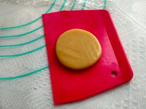 取出一块面团，搓成圆球状，用刮板压扁，拿起来放到一只手的虎口处，手上沾少许面粉，再把准备好揉成圆球的馅料放在面饼的中心处，用皮包住馅料，一点一点往上推，手一定要轻，不要露陷，尽量做到面皮均匀。