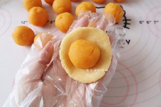 将20克的皮压扁后，放上奶黄流心馅，切记不要过度用力，以免流心爆出来。
