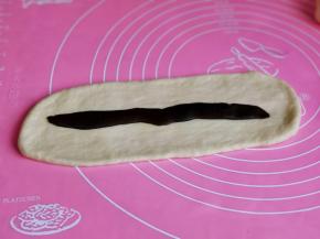 取一块面团用擀面杖擀长舌状，放上豆沙馅。