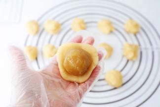 取一份饼皮，放在掌心按压成圆饼形，再放入白莲蓉蛋黄馅