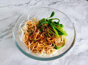 面条、豆芽、青菜捞到大一点的容器里面，淋上料汁，用筷子搅拌翻转，让每根面条能够与酱汁互相融合在一起。