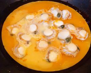 锅中倒入底油加热再倒入蛋液和扇贝肉肉