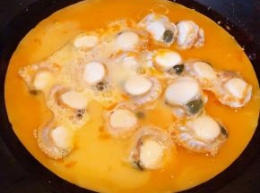 锅中倒入底油加热再倒入蛋液和扇贝肉肉