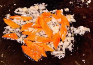 另起锅倒入底油加热放入蒜粒爆香再放入胡萝卜片炒至断生