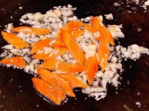 另起锅倒入底油加热放入蒜粒爆香再放入胡萝卜片炒至断生