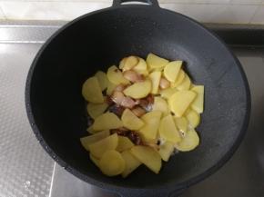然后锅里不需要额外再加油，直接倒入土豆片一起翻炒1-2分钟。然后将之前炒好的五花肉一起放入翻炒一会，倒入料酒，炒匀去腥。